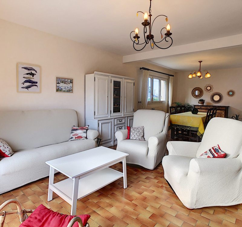 Location Saint Martin de Bréhal "Les Oyats" Salon spacieux avec vue et accès extérieure comprenant une cheminée.
